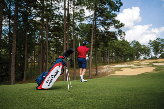 Male golfer hitting a golf ball with the Titleist golf bag behind him